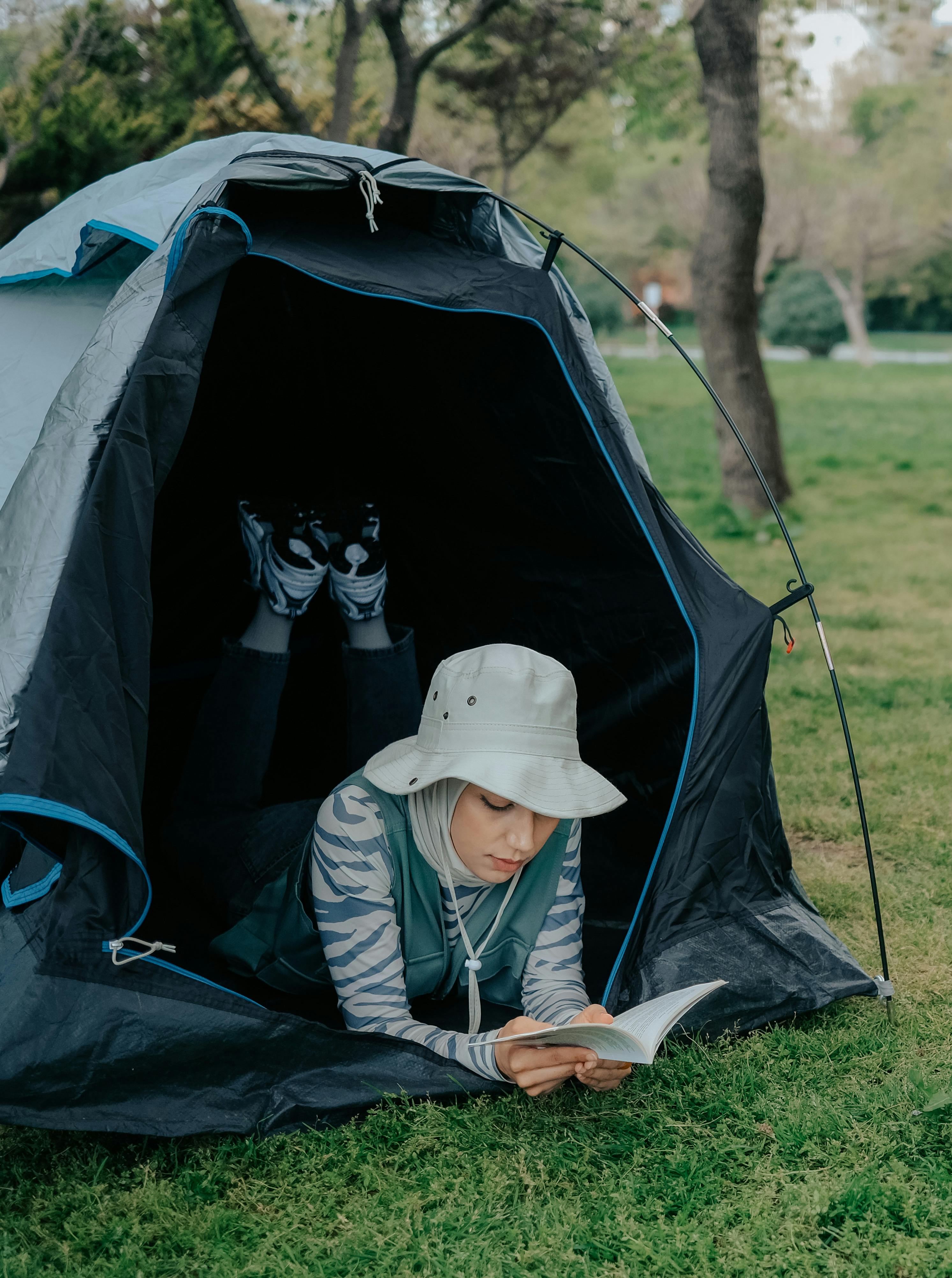 Relaxing moment as a woman reads a book inside a tent outdoors.