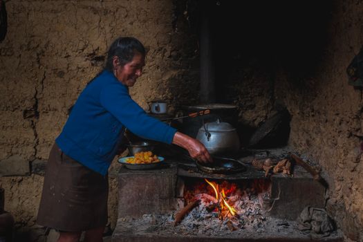A woman cooks over an open flame in a traditional kitchen in Chota, Cajamarca, Peru.