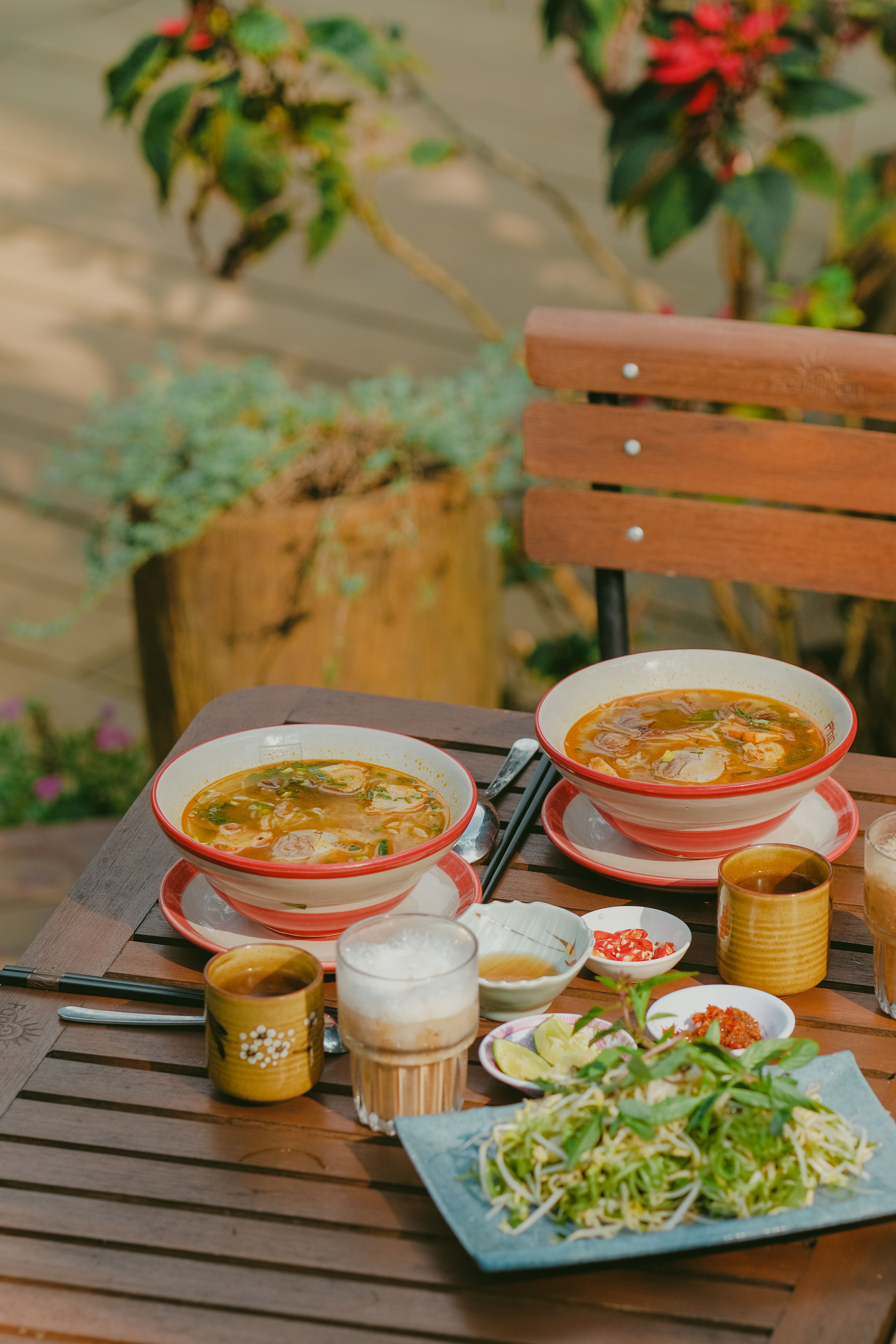 A cozy outdoor setting featuring two delicious bowls of soup accompanied by fresh ingredients.