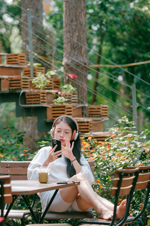 Free Teenage Girl Listening to Music on Headphones and Checking her Phone  Stock Photo