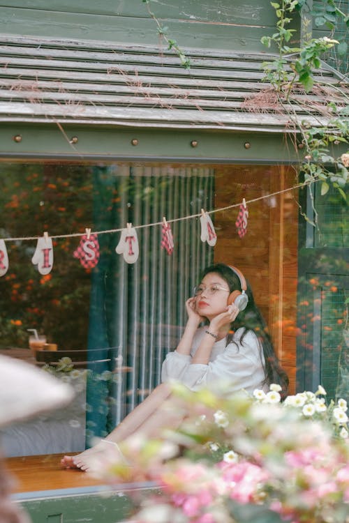 Free Teenage Girl Sitting in the Window and Listening to Music on Headphones  Stock Photo