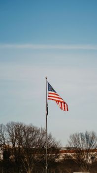 American flag waving on a flagpole with clear blue sky in the background.