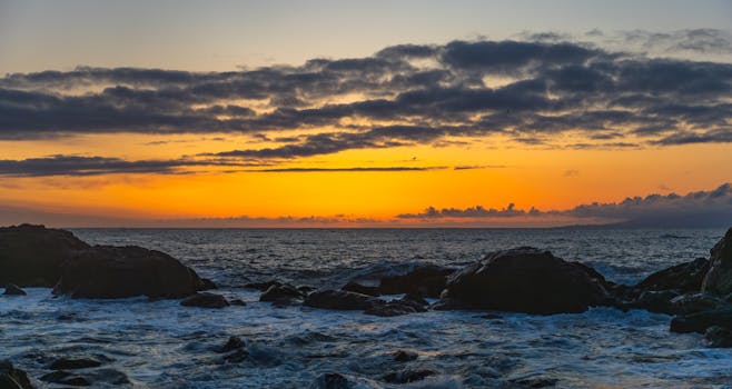 Captivating seascape at sunrise featuring rocks, vibrant sky, and ocean waves.