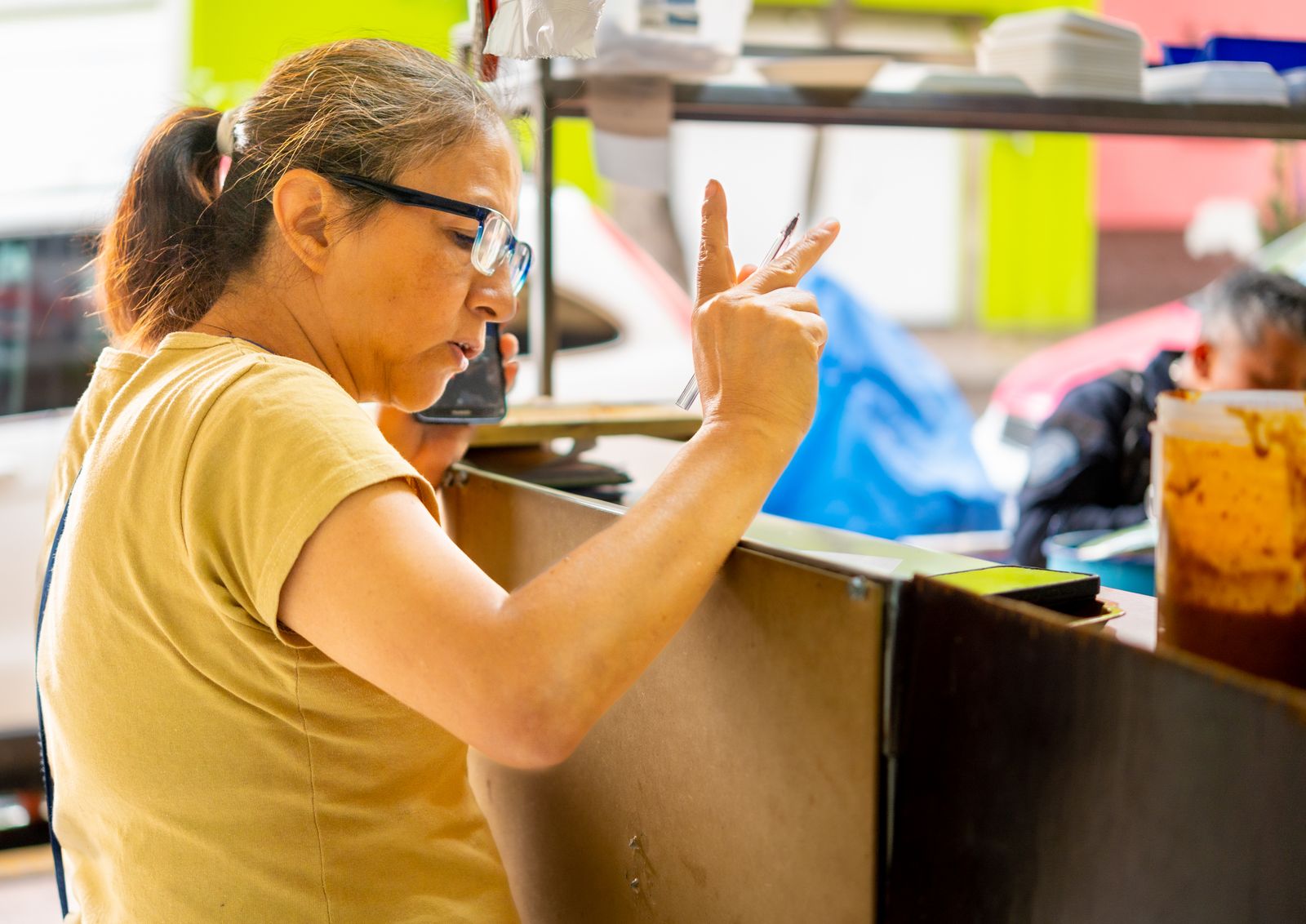 Profissional de alimentação registrando pedido com smartphone em ambiente de restaurante