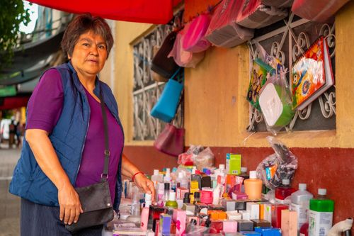 Free Woman selling cosmetics at an outdoor market stall, highlighting colorful beauty products. Stock Photo