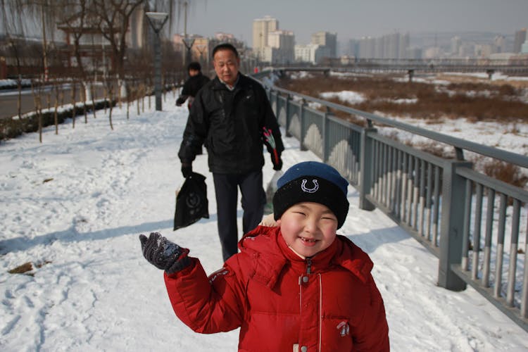 Boy Walking With His Father Behind On A Winter Day