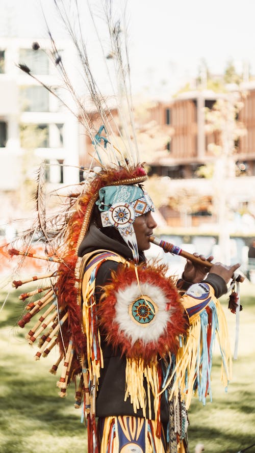 Man in Traditional, Native American Clothing Playing Flute