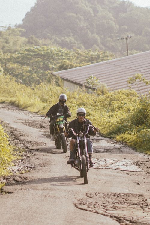 Free Two bikers on motorcycles navigate a rural West Java road with lush greenery. Stock Photo