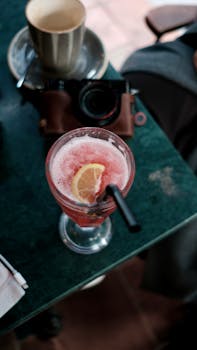 Top view of a citrus cocktail with a lemon slice on a café table with a camera.