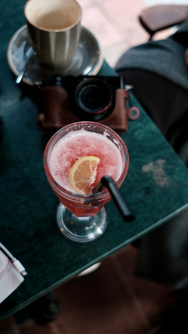 A Cocktail, A Camera And A Cup On A Table 