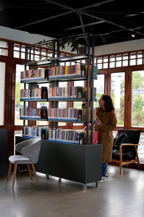 Free A woman in a modern library is browsing books on organized shelves. Stock Photo