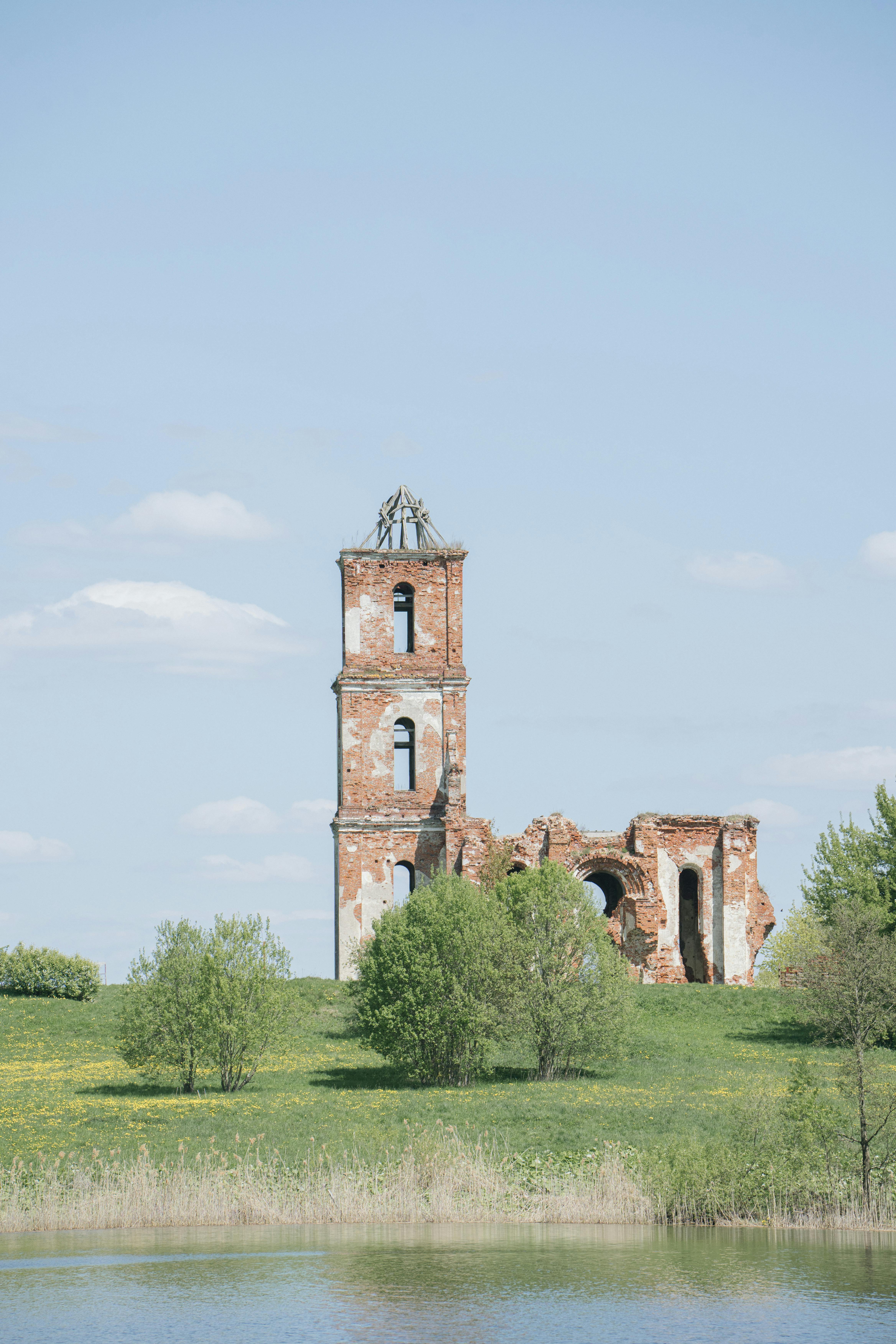 A scenic view of ancient church ruins on a grassy landscape in Belarus.