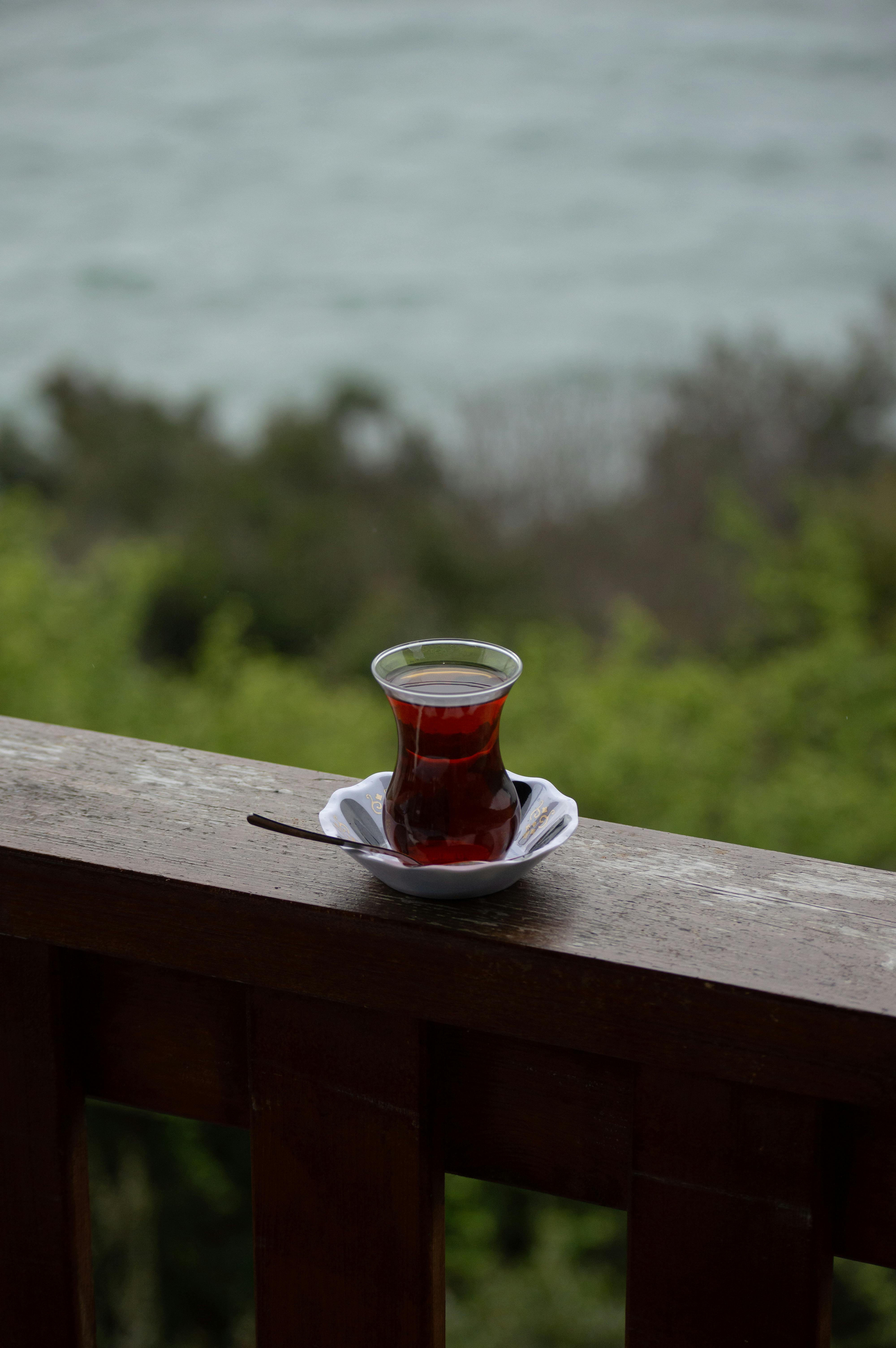 Glass of Turkish tea on a wooden balcony with a view of nature and water in Istanbul, Turkey.