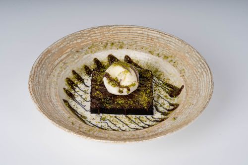 Free A rich brownie topped with ice cream and garnished with chocolate drizzle on a rustic plate. Stock Photo