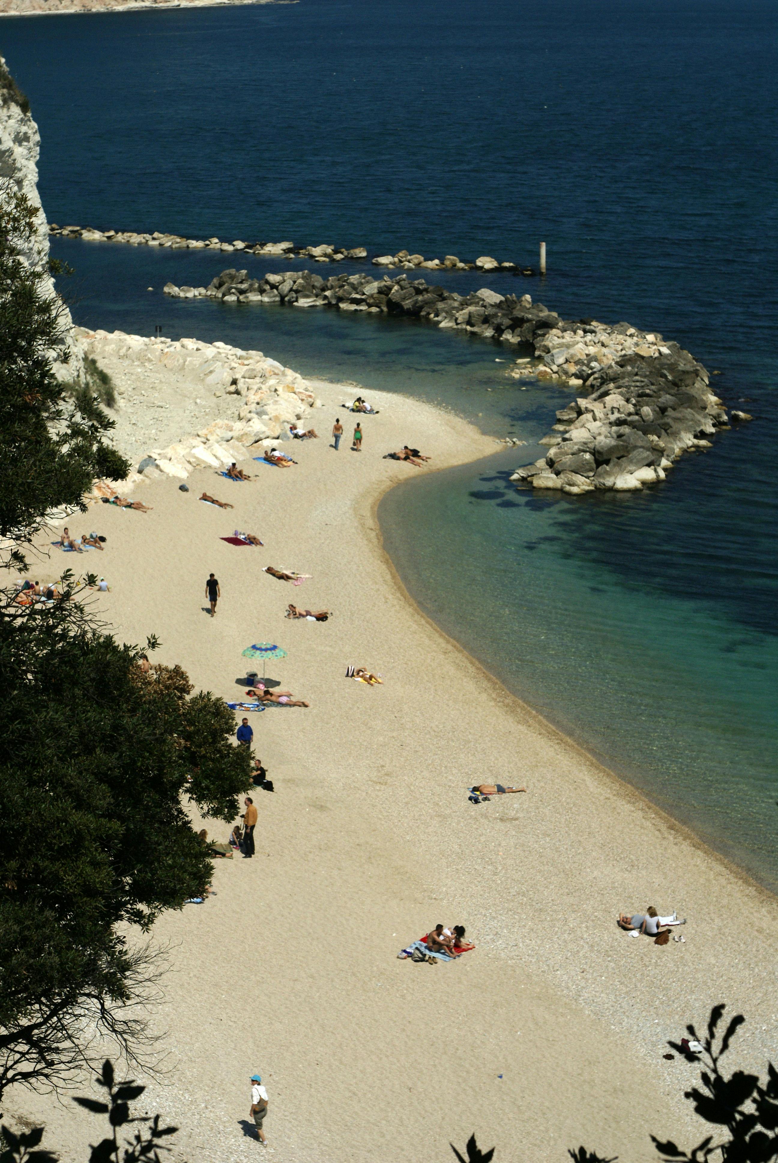 a beach with people on it and a rocky shore