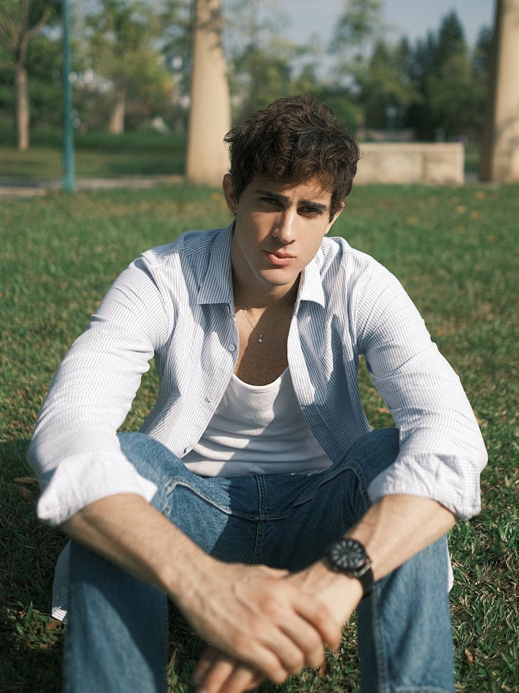 Man In Jeans And A Shirt Sitting On The Lawn