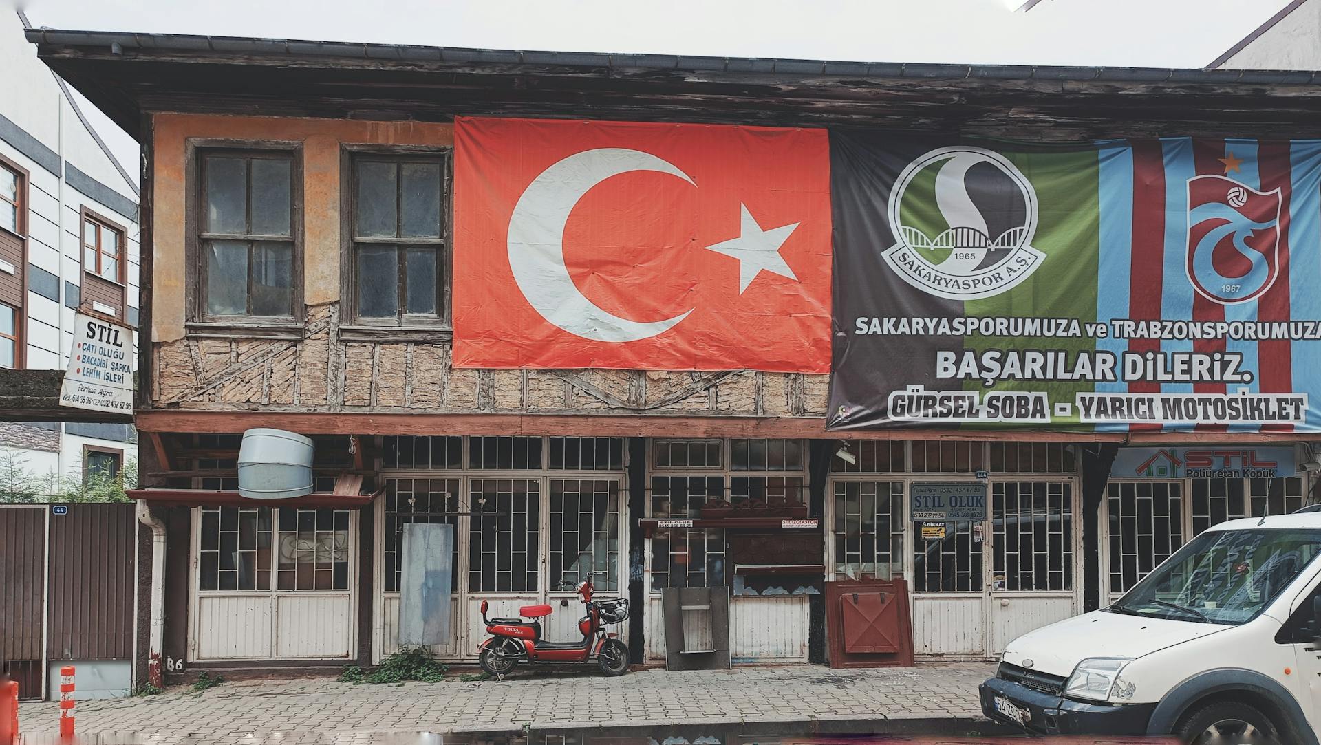 A street view showcasing a building with Turkish flag and sports banners, capturing local pride.