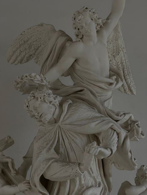 Intricately carved marble angel statue with detailed human figures.