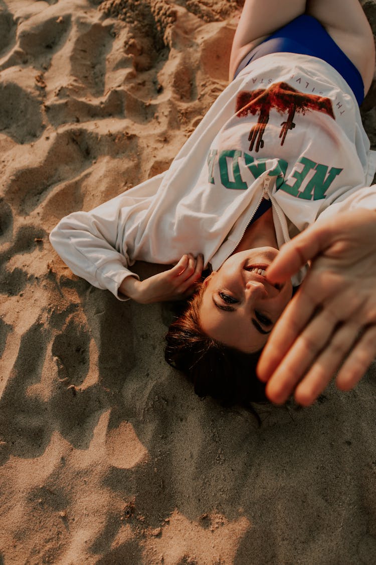 Young Woman Lying On The Beach And Smiling 