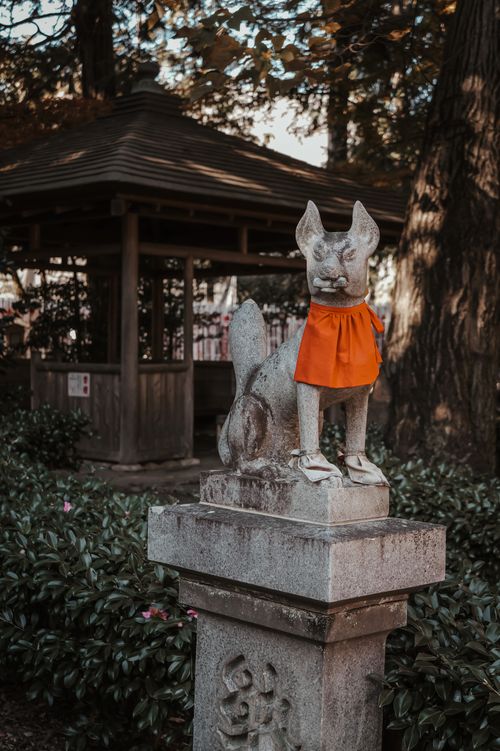 Free A stone fox statue with red cloth in a serene Toyokawa park setting, Japan. Stock Photo