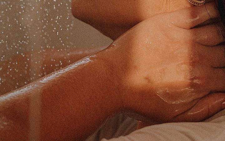 Adult woman enjoying a soothing shower in warm, natural lighting indoors.
