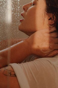 Adult woman enjoying a soothing shower in warm, natural lighting indoors.