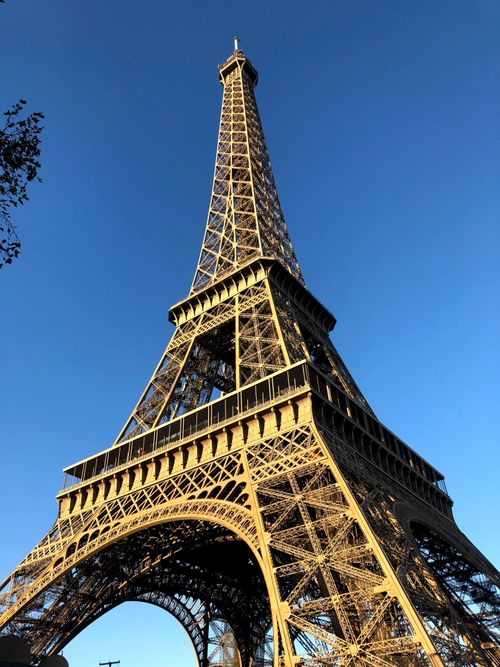 Free A striking low angle view of the Eiffel Tower in Paris against a clear blue sky. Stock Photo