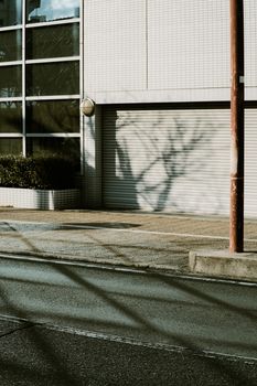 An urban street scene featuring building shadows and a closed garage door.