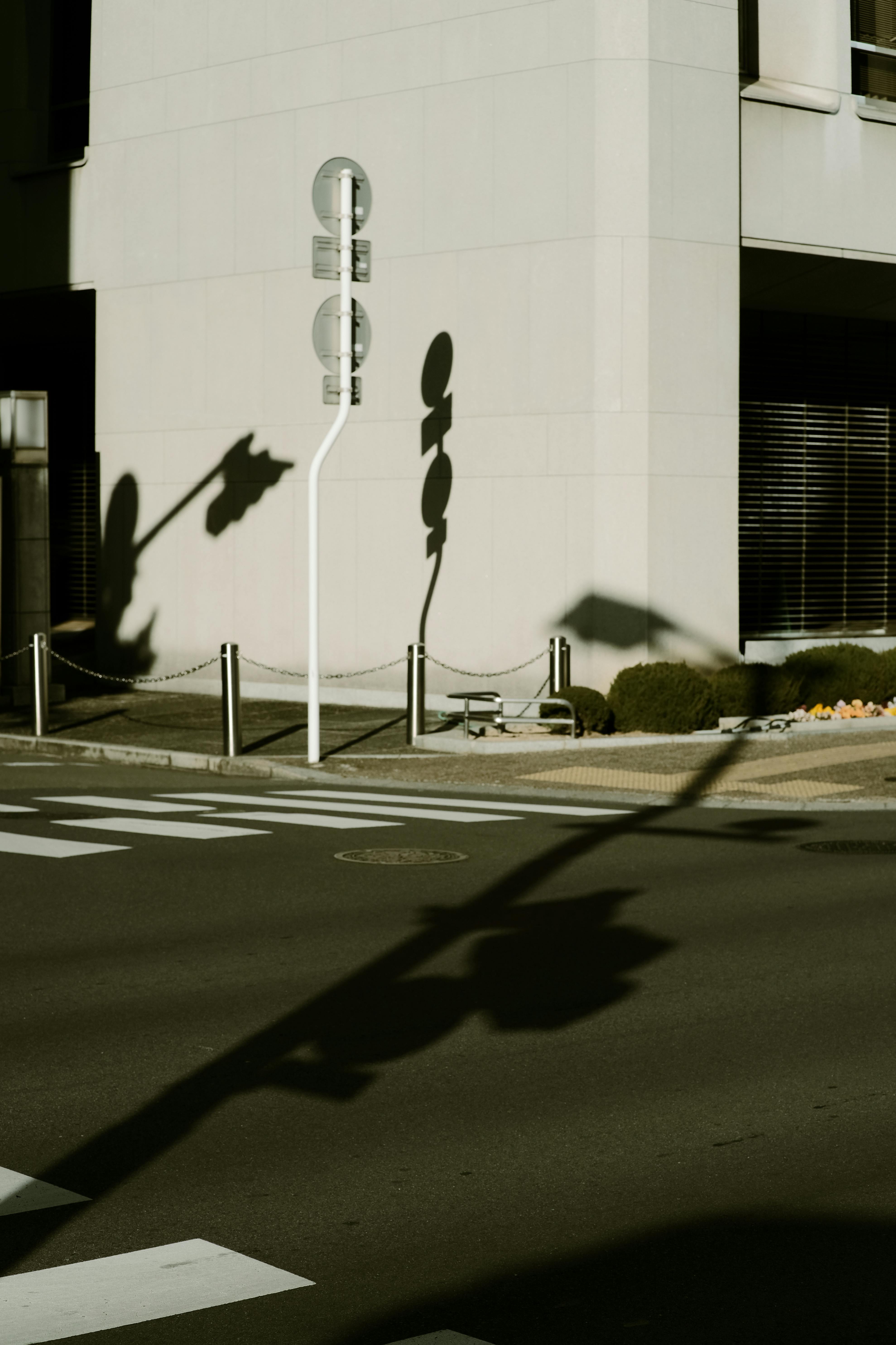 Street corner with building and traffic sign shadows in city sunlight.