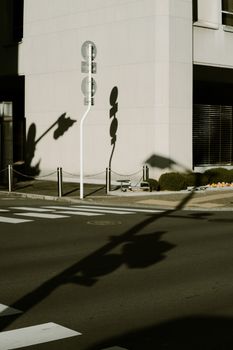 Street corner with building and traffic sign shadows in city sunlight.