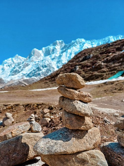 Free Rock stacks with snowy mountains create a serene and natural scenic view. Stock Photo