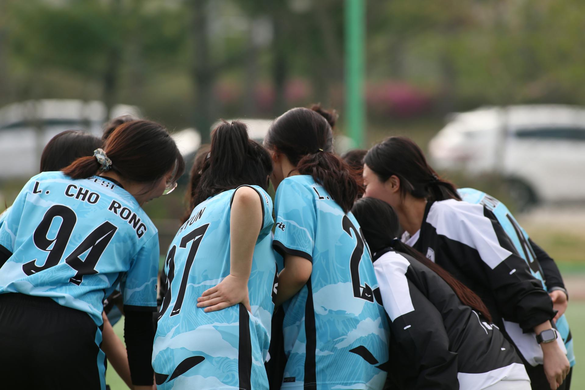 A group of female football players huddling together for a team pep talk during a match.