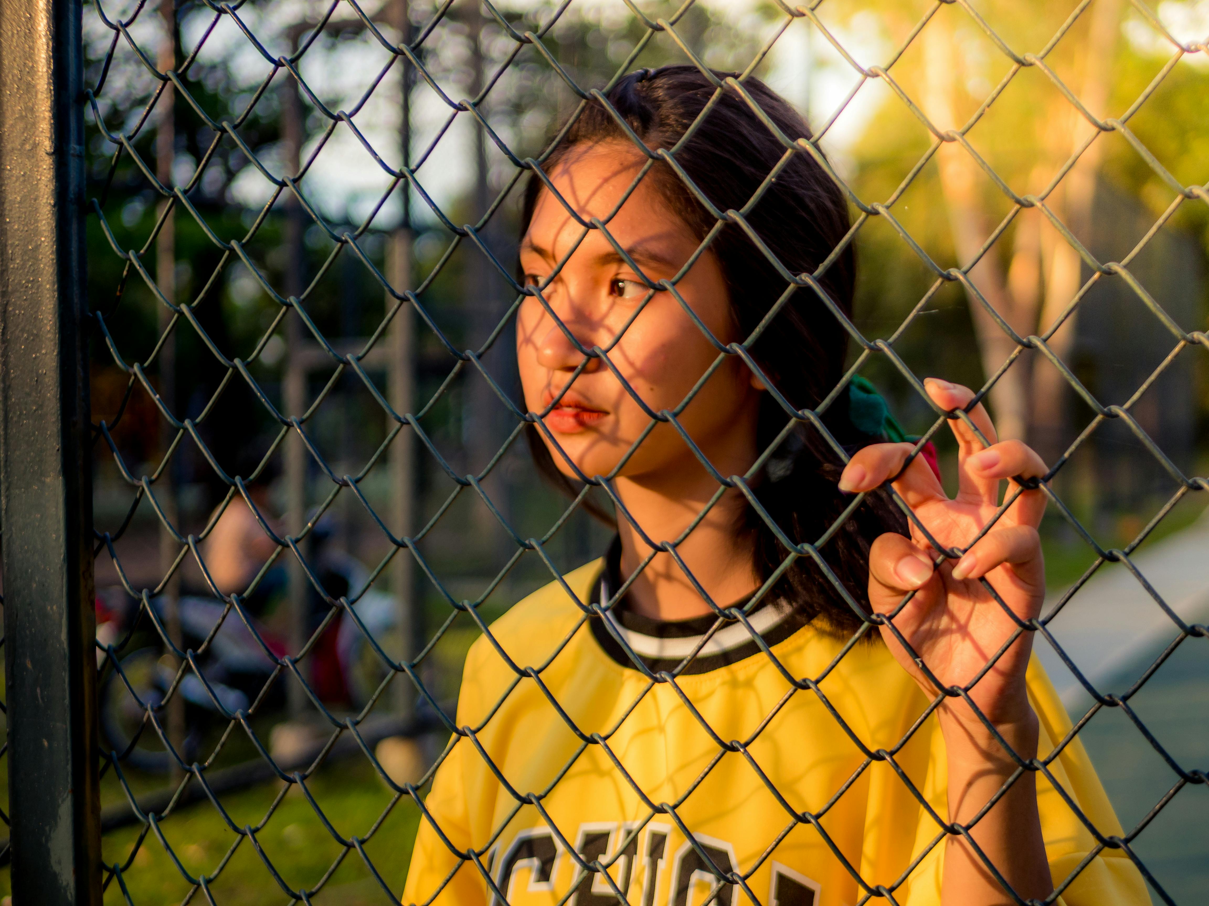 photo of woman holding on fence