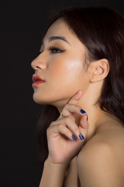 A stunning side profile portrait of a young woman on a black background, showcasing beauty and elegance.