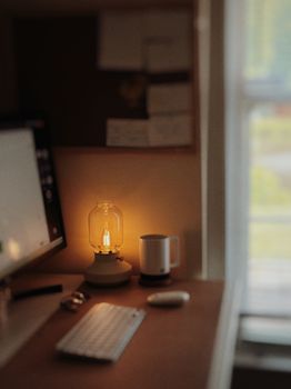 A cozy workspace featuring a glowing lamp, keyboard, and mug, perfect for productivity.