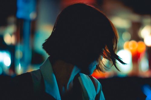Free Silhouette of a woman at night with urban neon lights creating a moody atmosphere. Stock Photo