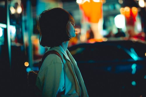 Free Artistic night portrait of a young woman in Hong Kong's bustling urban nightlife. Stock Photo