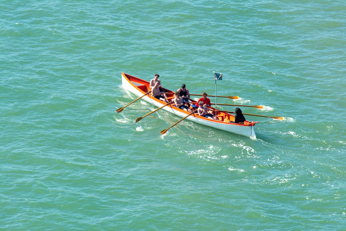 A group of people rowing a boat in the ocean · Free Stock Photo