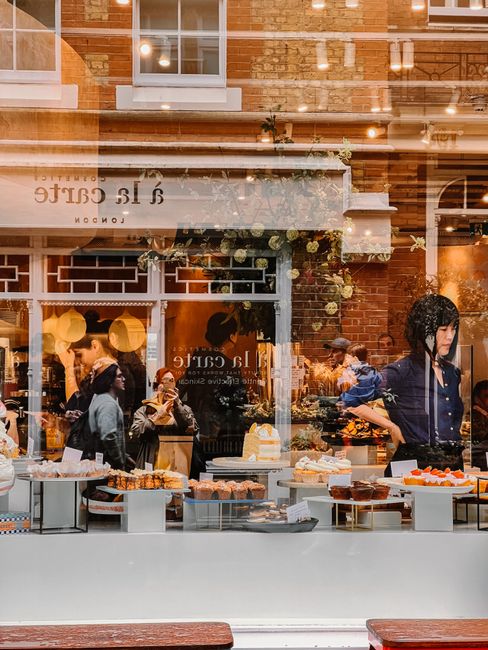 A lively urban cafe showcases a tempting array of pastries through its large window.
