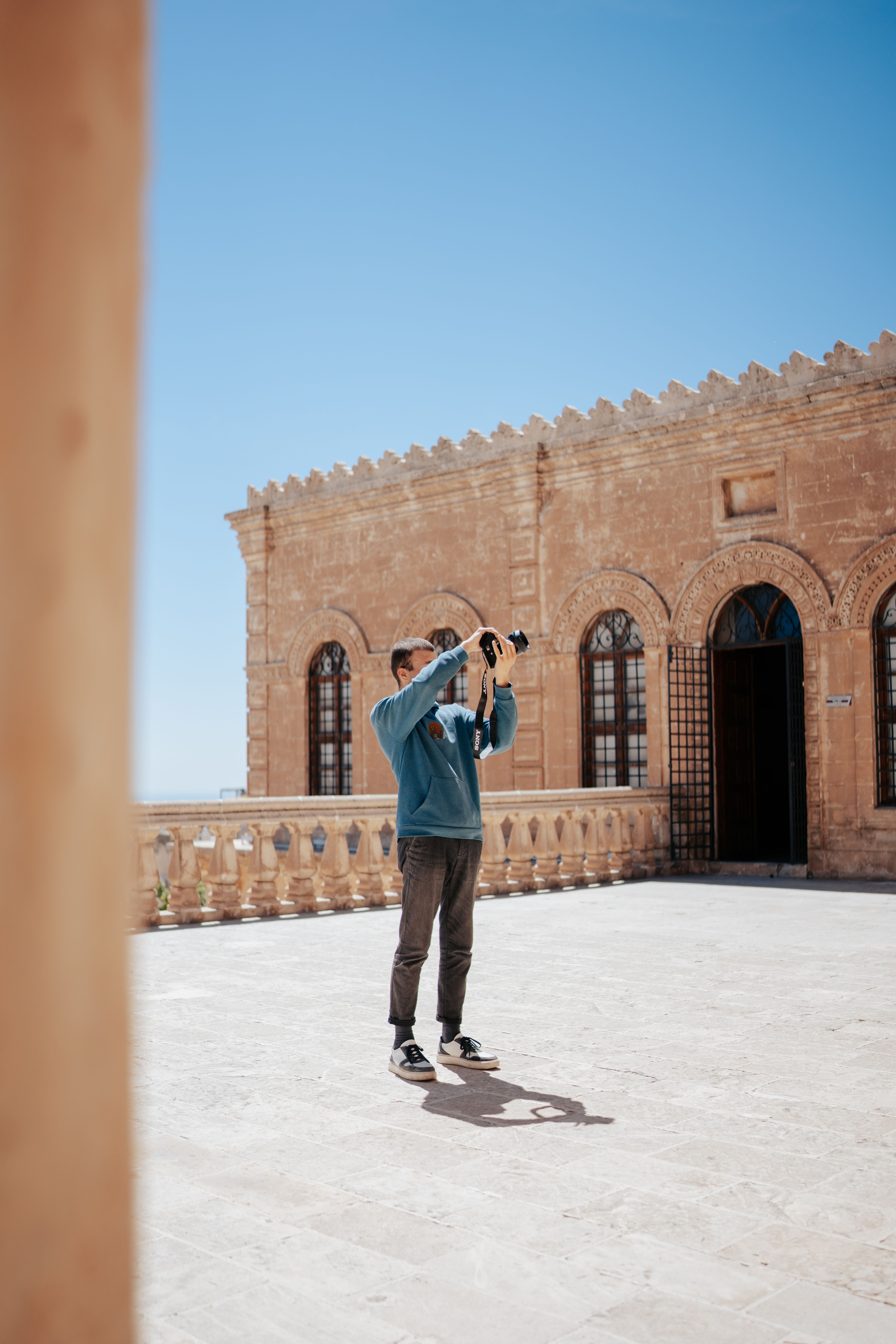 Man taking photos of a historic stone building on a sunny day - historical marker photography