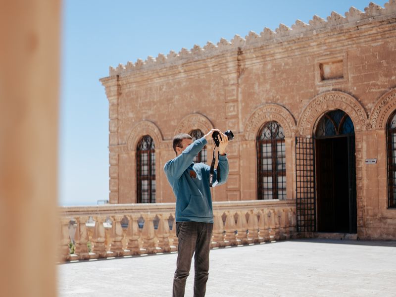 Man taking photos of a historic stone building on a sunny day - historical marker photography
