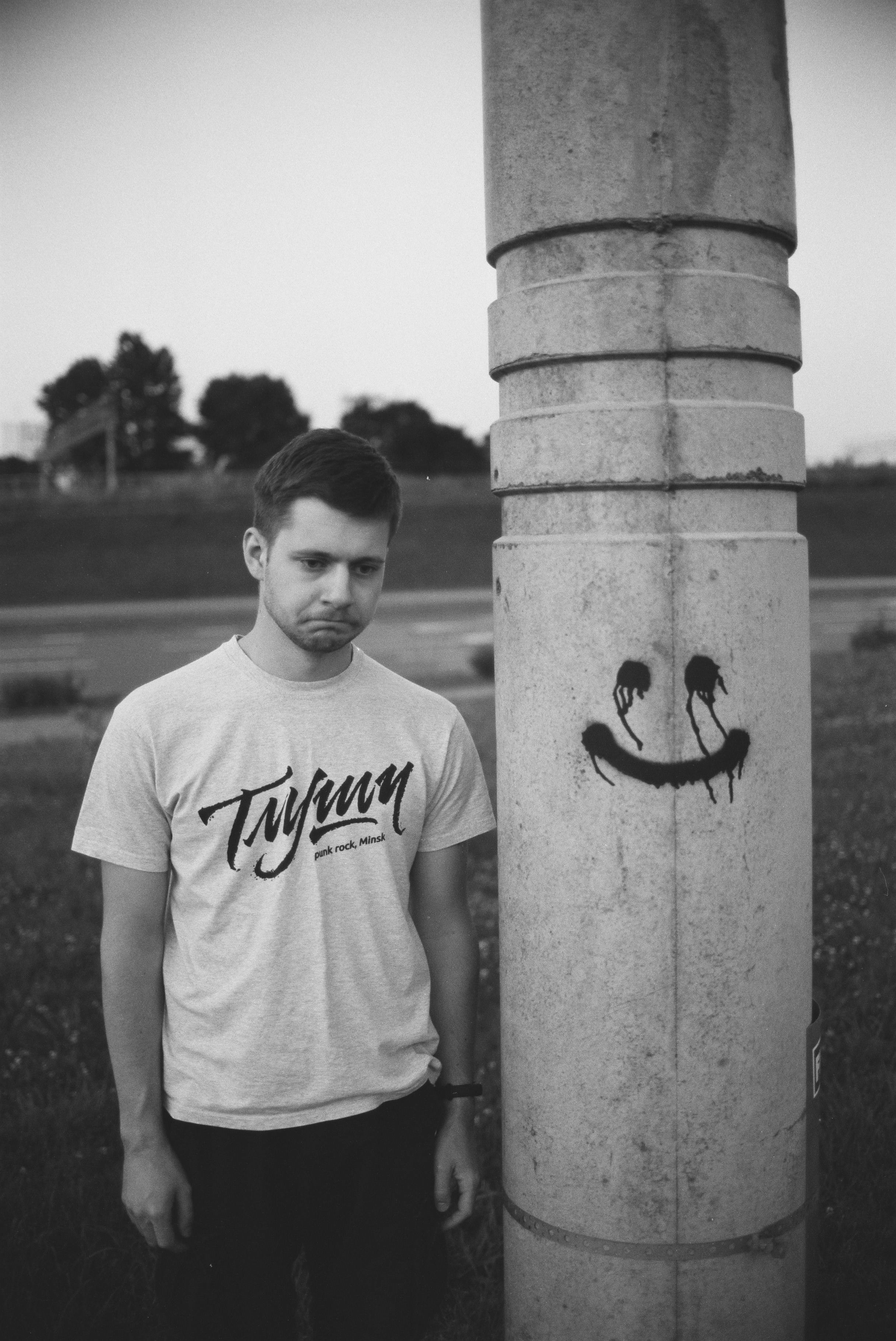 A young man posing by a pole with graffiti art in Minsk, Belarus.