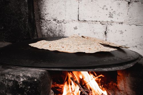 Free Turkish flatbread gozleme being cooked over an open hearth flame in Malatya, Türkiye. Stock Photo