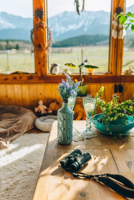 A bright interior with mountain views, featuring decor items and binoculars on a wooden table.