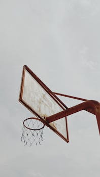An old basketball hoop under a cloudy sky in East Java, Indonesia, symbolizing urban decay.