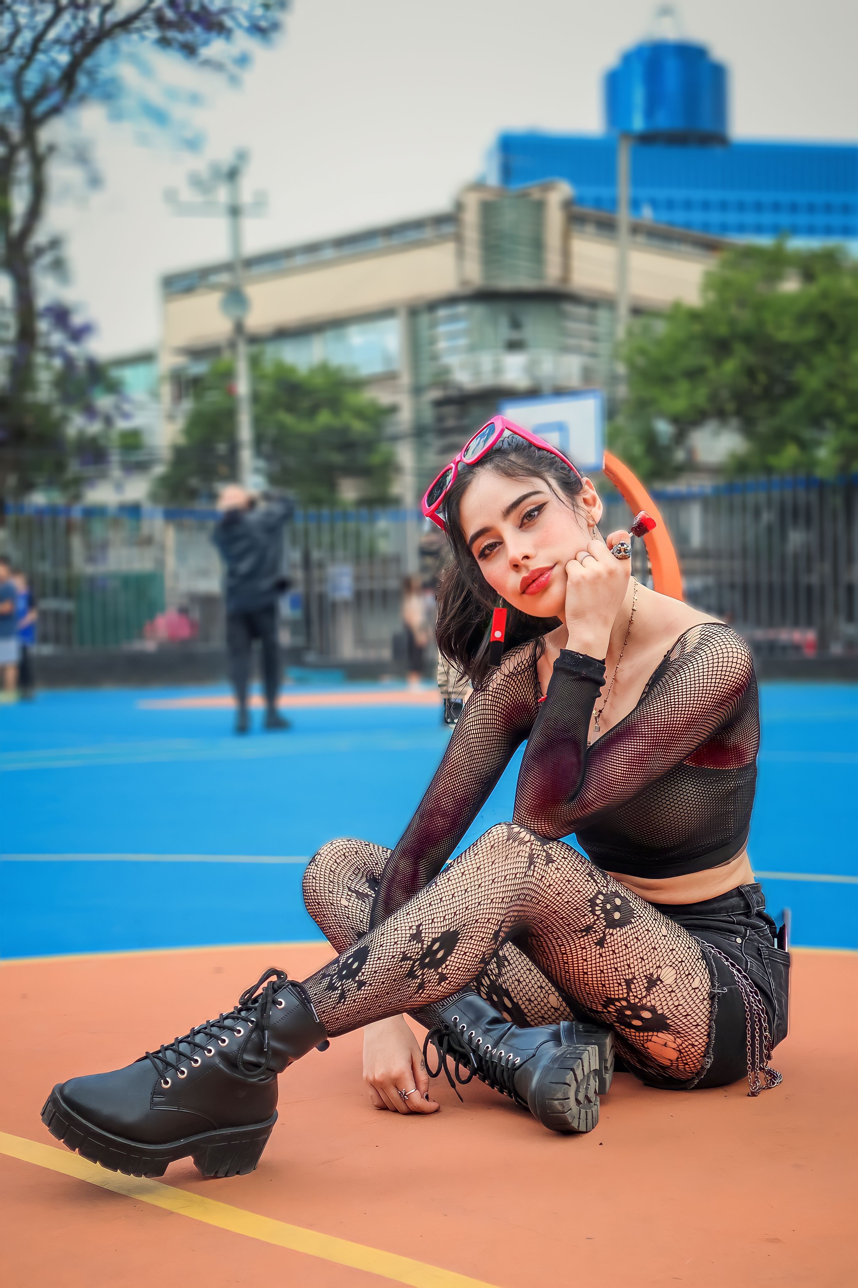 Mulher com estilo eclético sentada em uma vibrante quadra de basquete ao ar livre.