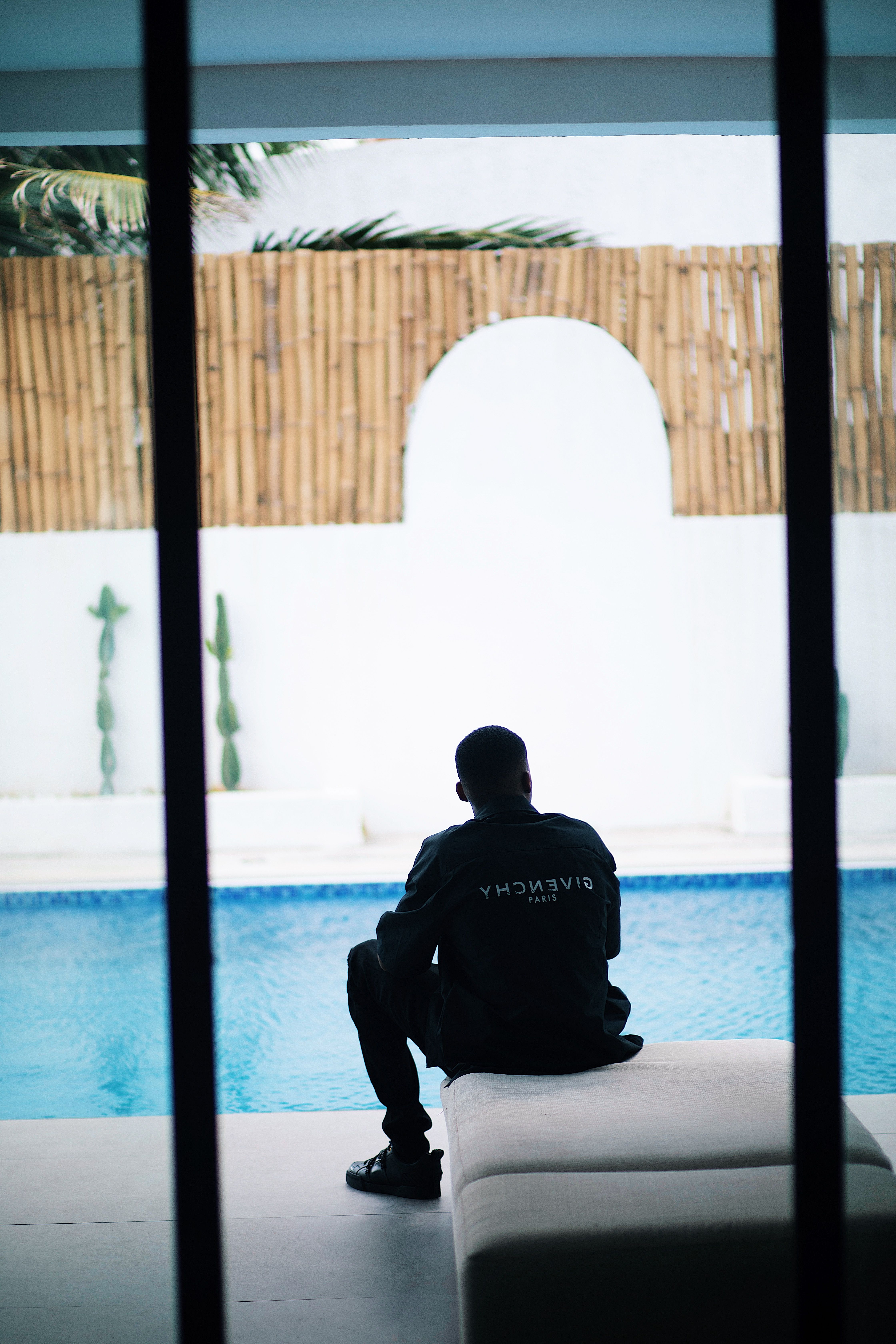 Silhouetted man sitting by a pool, evoking a sense of calm and luxury.