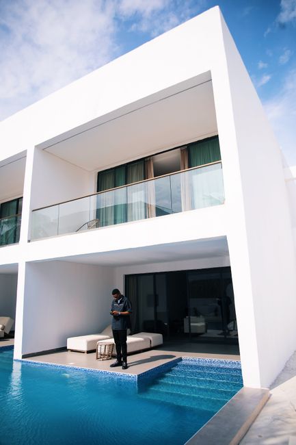 Contemporary apartment exterior with swimming pool and man standing on terrace in Lagos, Nigeria.