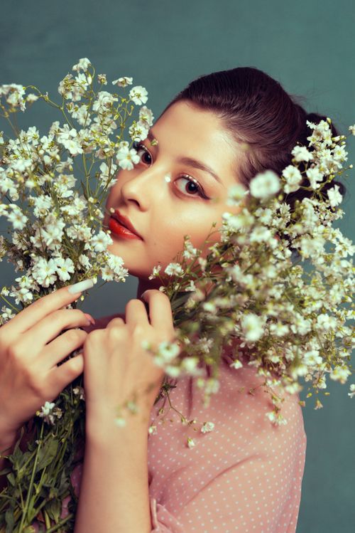 Free A captivating portrait of a woman surrounded by delicate white flowers, exuding grace and beauty. Stock Photo