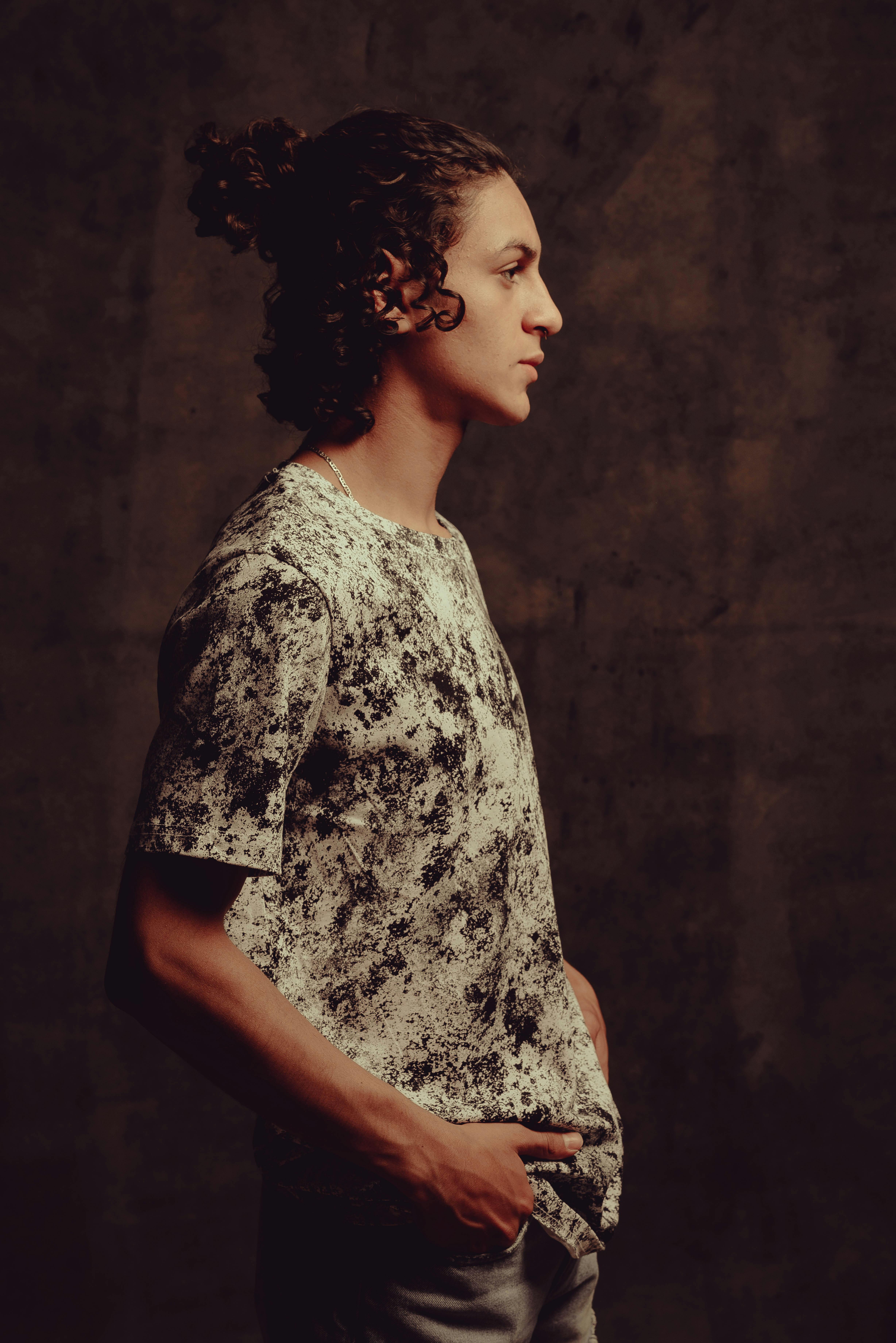 Artistic studio portrait of a fashionable young man with curly hair, exuding confidence.
